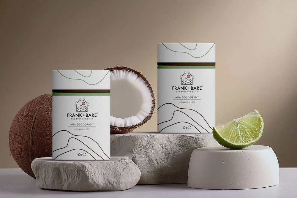 Two natural deodorant tubes of Frank & Bare products with a coconut, lime, and stone on a neutral background